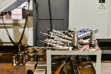 Mandrels and accessories for the CNC milling machine are located on the machine near the industrial equipment. Drills, cutters, cutters for metal processing.