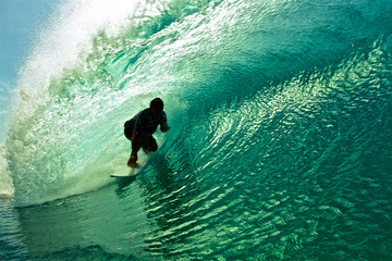 Surfer silhouette riding wave inside the tube barrel
