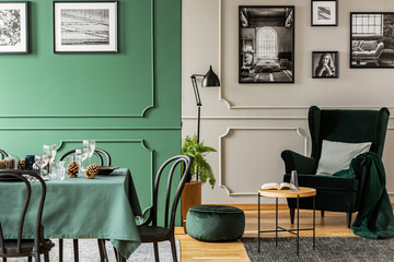 Open plan living and dining room interior with table with chairs and emerald green armchair