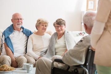 Fototapeta premium Group of senior friends sitting together in common living room of nursing home