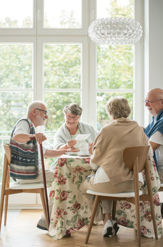 Senior friends spending time together by drinking tea and enjoying photos