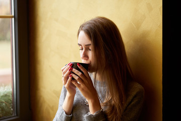 Young pretty girl with long hair drinking coffee or tea  in the cafe.