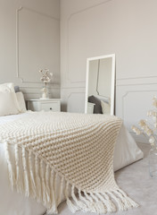 Fototapeta na wymiar Cozy cream colored woolen blanket on king size bed in bright bedroom
