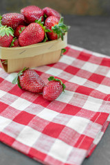 Fresh Strawberries in Basket with two Isolated on red and white checked napkin on black background