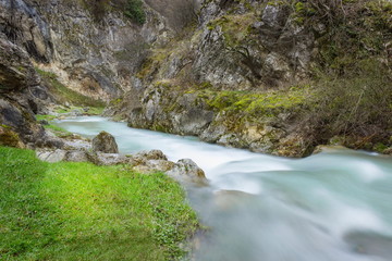 Cold mountain creek flowing down the vibrant, narrow, rocky canyon, lighten by the sun