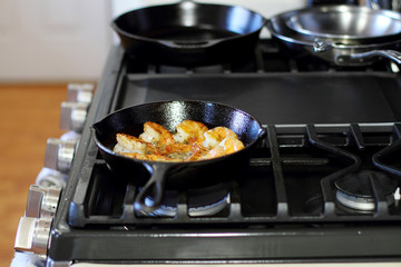 Shrimp Scampi cooking in a cast iron pan on the stove.