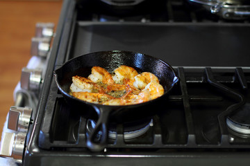 Shrimp Scampi cooking in a cast iron pan on the stove.