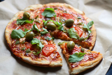 Homemade vegetarian pizza with tomato sauce, two types of cheese, tomatoes, peppers, arugula, olives and herbs. Selective focus.