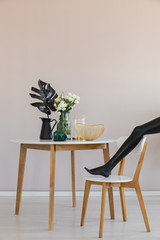 Black mannequin's leg on chair in trendsetting dining room interior with copy space on empty pastel...
