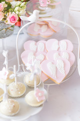 Sweet table at Christening or First Communion party. Heart shaped cookies with angel wings.
