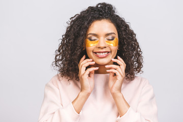 Image of young pure beautiful afro american woman standing naked isolated against white take care of her skin with under eye patches.