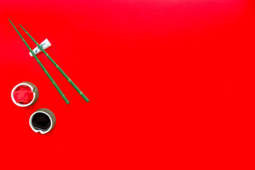 Japanese food cooking set with soy sauce, ginger, bamboo sticks for sushi on red background top view copy space