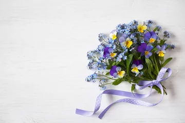Foto op Plexiglas A bouquet of forget-me-nots and pansies on a wooden background © tachinskamarina