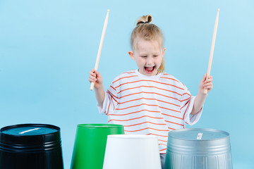 Little jolly boy using drumsticks on iron and plastic buckets. Playing rhythm. © zzzdim