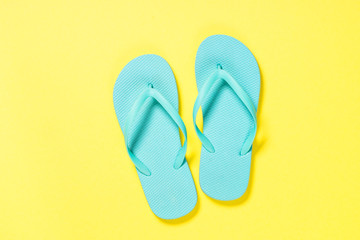 Blue flip flops on yellow background.
