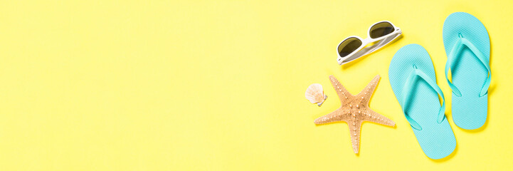 Blue flip flops, swimsuit, sunglasses and starfish on yellow background.