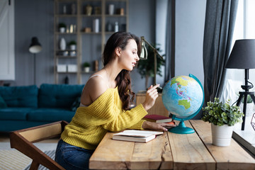 Woman chooses a place to travel on the globe sitting at home.