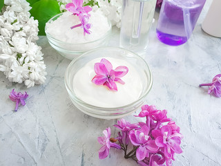 Fototapeta na wymiar cream cosmetic flower lilac on a gray concrete background