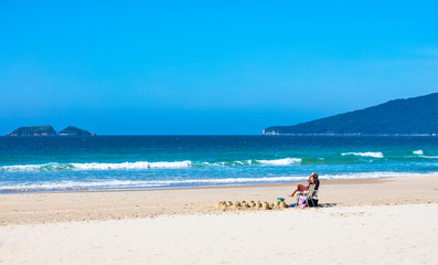 Fototapeta na wymiar Pessoa sentada na cadeira em uma praia
