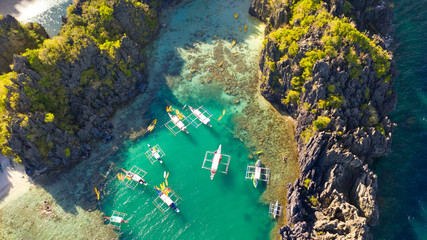 Aerial drone view of kayaks inside a beautiful shallow tropical lagoon surrounded by jagged cliffs and jungle Small Lagoon, El Nido