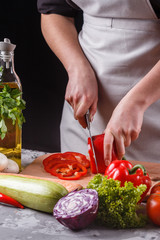 young woman slicing peppers in a gray apron
