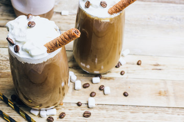 Ice coffee in a tall glass on a old rustic wooden table. Cold summer drink