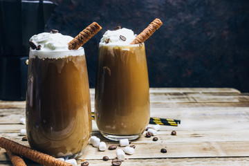 Ice coffee in a tall glass on a old rustic wooden table. Cold summer drink