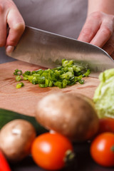 young woman slicing herbs in a gray apron
