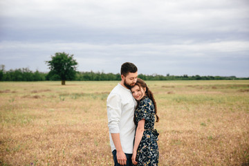 beautiful loving couple resting in summer field on dry grass background