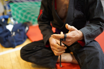 Brazilian jiu jitsu BJJ fighter using tape to strengthen taping his fingers at the tournament...
