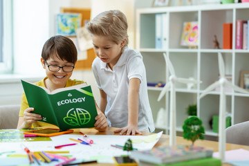 Curious smart boys observing educative book about ecology