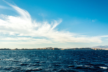 Seascape, view of the blue sea with high bald mountains in the background