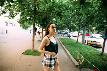 Brunette girl in a summer day in the city wearing round sunglasses
