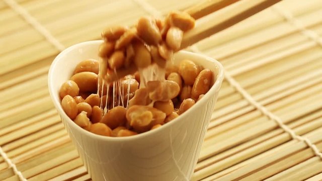 Eating healthy traditional japanese fermented soybeans called natto with chopsticks