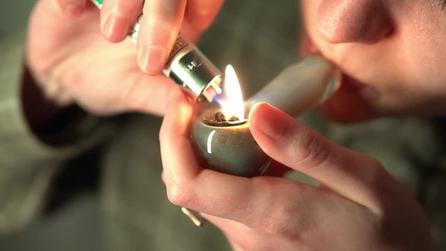 Slow motion smoking cannabis through a glass tube. Soft drug use by young people.