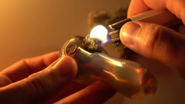 Slow motion smoking cannabis through a glass tube. Soft drug use by young people.