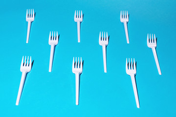 White plastic forks on blue background.