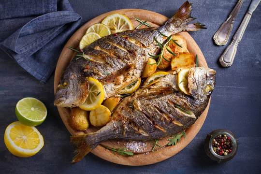 Roasted fish and potatoes, served on wooden tray. overhead, horizontal - image