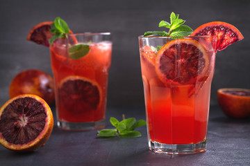 Two glasses of blood orange or red orange cocktail with slices of citrus fruits and mint - image