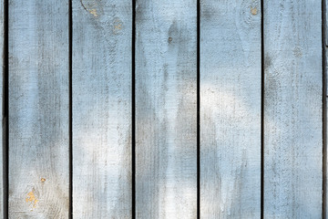 Horizontal photo of gray wooden planks. Against the background of several scattered sunspots. Background of vertical natural old wooden planks.