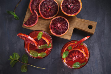 Two glasses of blood orange or red orange cocktail with slices of citrus fruits and mint - image