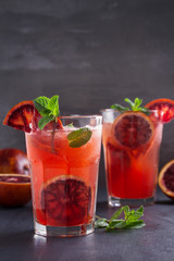 Two glasses of blood orange or red orange cocktail with slices of citrus fruits and mint - image