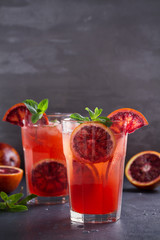 Two glasses of blood orange or red orange cocktail with slices of citrus fruits and mint - image