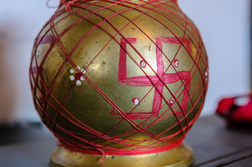Hindu swastika symbol on a brass vase at a Hare Krishna Temple