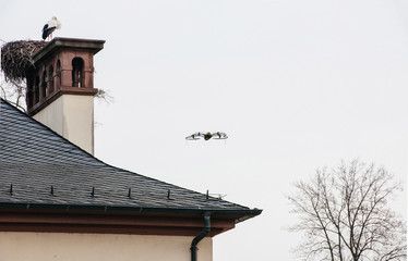 Modern drone flying near stork nest on the roofs of old building in Strasbourg, Alsace, France 