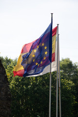 Flag of Spain and the European Union together and superimposed waving in front of the blue sky.