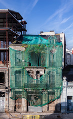 Old stone building uninhabited and in ruins, covered by a green cloth. Galician city of Lugo, Spain.