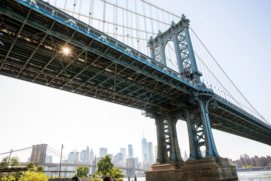 A view from below of the Manhattan Bridge on the Brooklyn waterfront with the city of New York in the background. - Powered by Adobe