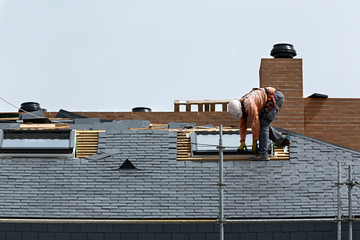Obrero trabajando en el tejado de pizarra de un edificio.