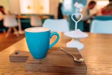 Hot cappuccino coffee in coffee shop on wooden table